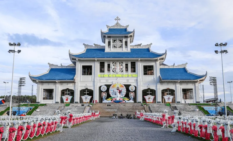 Nhà thờ mái ngói xanh kiểu chùa với sân rộng trang trí hoa đỏ trắng gần Huế.