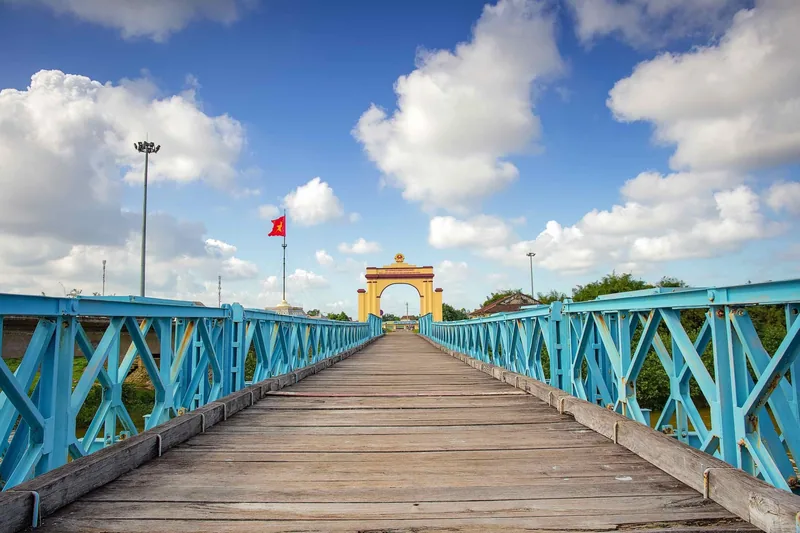 Lối đi gỗ giữa hai hàng thép màu ngọc dẫn tới cổng vòm màu vàng tại cầu Hiền Lương, Quảng Trị.