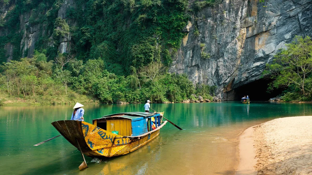 Một chiếc thuyền gỗ truyền thống lướt trên dòng nước xanh ngọc hướng vào cửa động Phong Nha.
