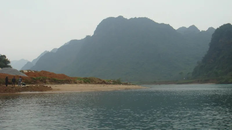 Núi đá vôi sừng sững bên dòng sông êm ả với bãi cát ven bờ gần Phong Nha.