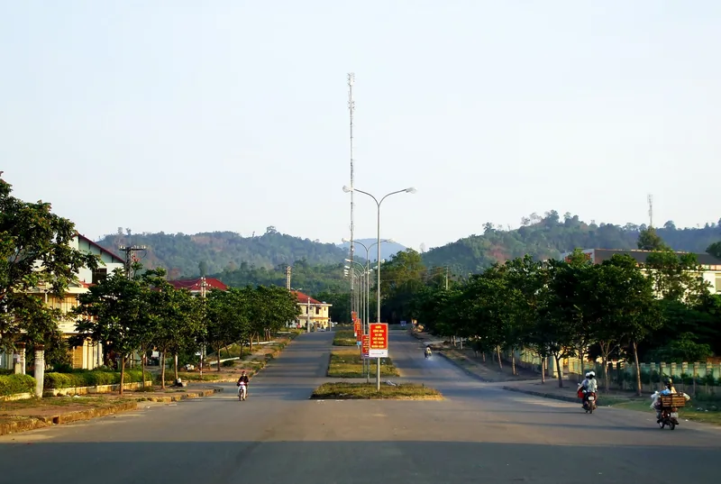 Đại lộ rợp bóng cây với người đi xe máy hướng về đồi núi xanh ở Lao Bảo, Quảng Trị.