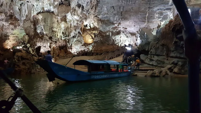 Thuyền du lịch neo trên sông ngầm trong động Phong Nha, ánh sáng chiếu lên các nhũ đá đá vôi hùng vĩ.