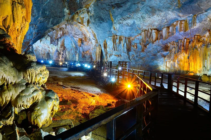 Lối đi bằng gỗ uốn lượn giữa những nhũ đá được chiếu sáng rực rỡ trong Động Thiên Đường, Việt Nam.