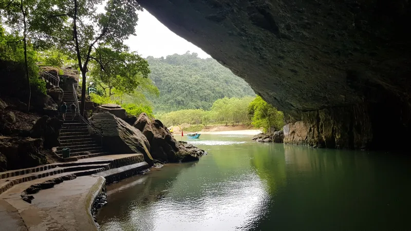 Cầu thang đá dẫn dọc theo dòng sông êm đềm chảy dưới cửa hang giữa rừng xanh ở Phong Nha.