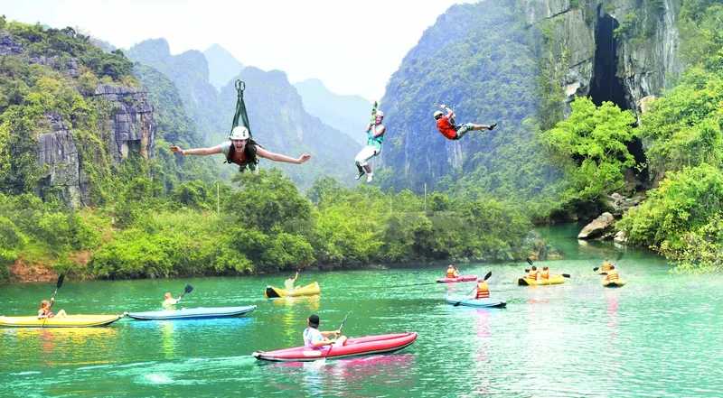 Người chơi zipline lướt qua dòng sông xanh ngọc với nhiều kayak màu sắc giữa núi đá vôi ở Quảng Bình.