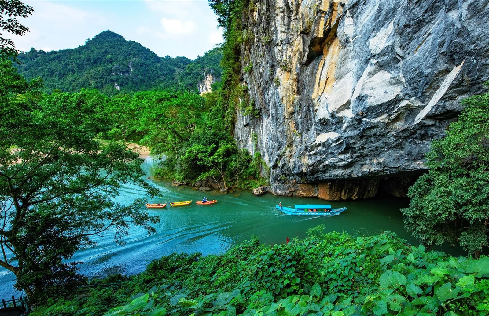 Những chiếc thuyền nhỏ lướt trên dòng sông xanh ngọc tiến vào cửa hang đá vôi Phong Nha.